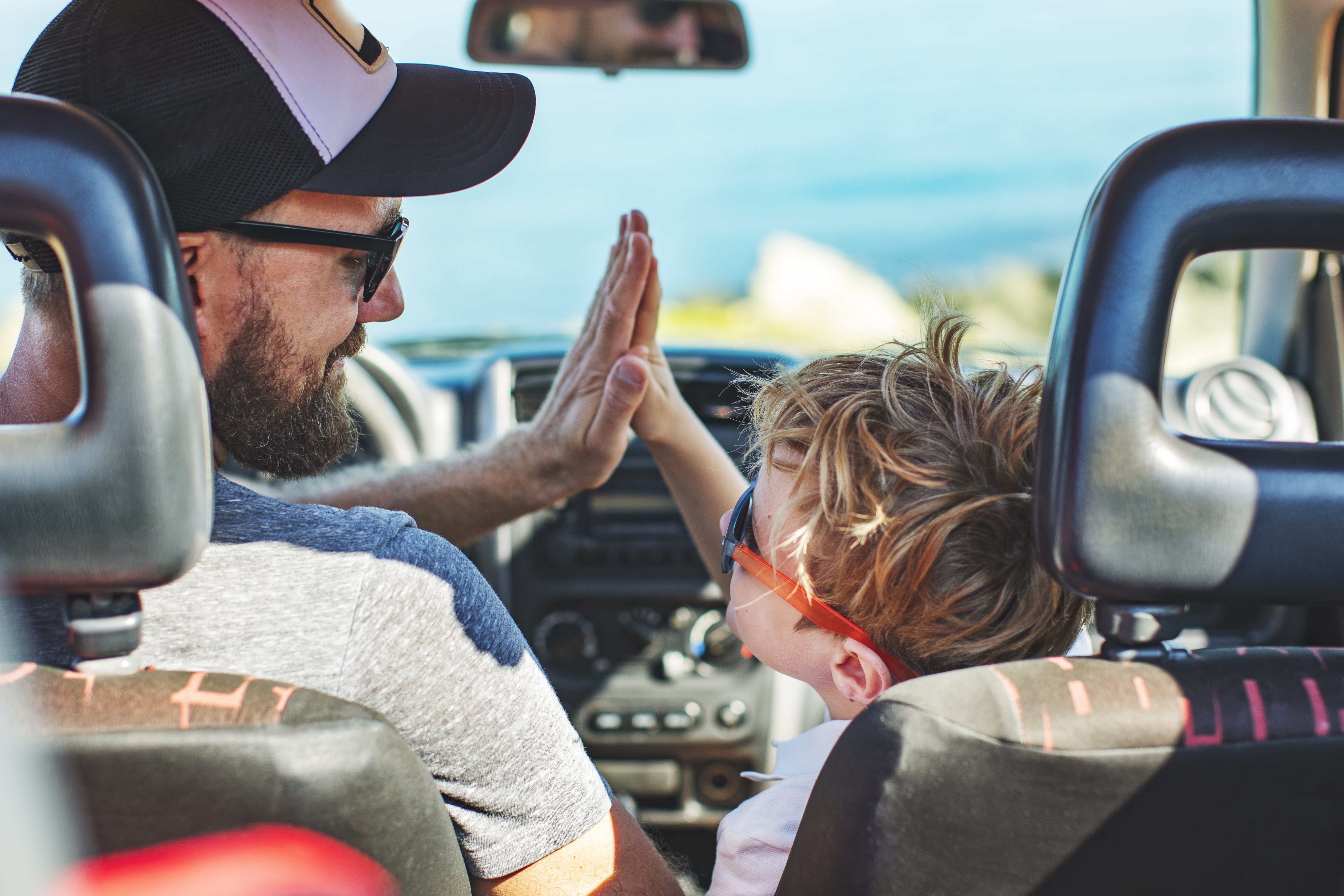 Far og sønn som gjør high-five i bilen