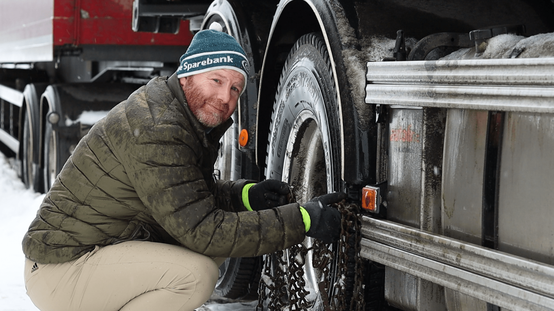 Mann legger på kjetting på lastebil