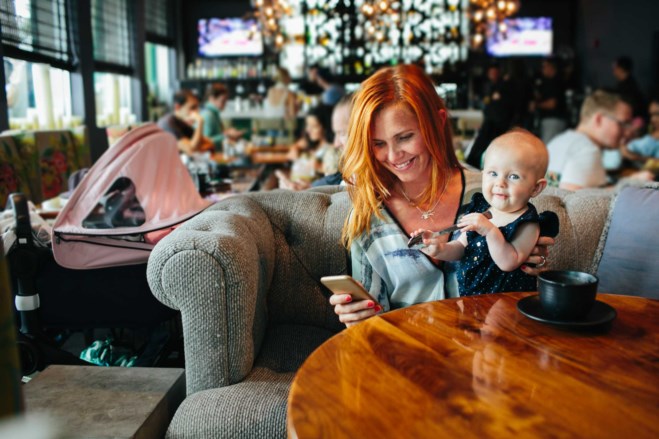 Tilfreds dame på barselkafe, med bankid på mobil